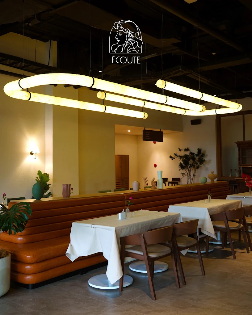 Wide view of the Écoute dining room, illuminated ceiling feature and leather banquette